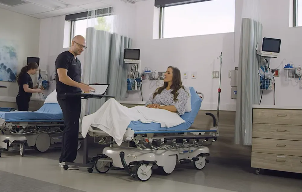 Doctor talking to female patient who is in hospital bed.