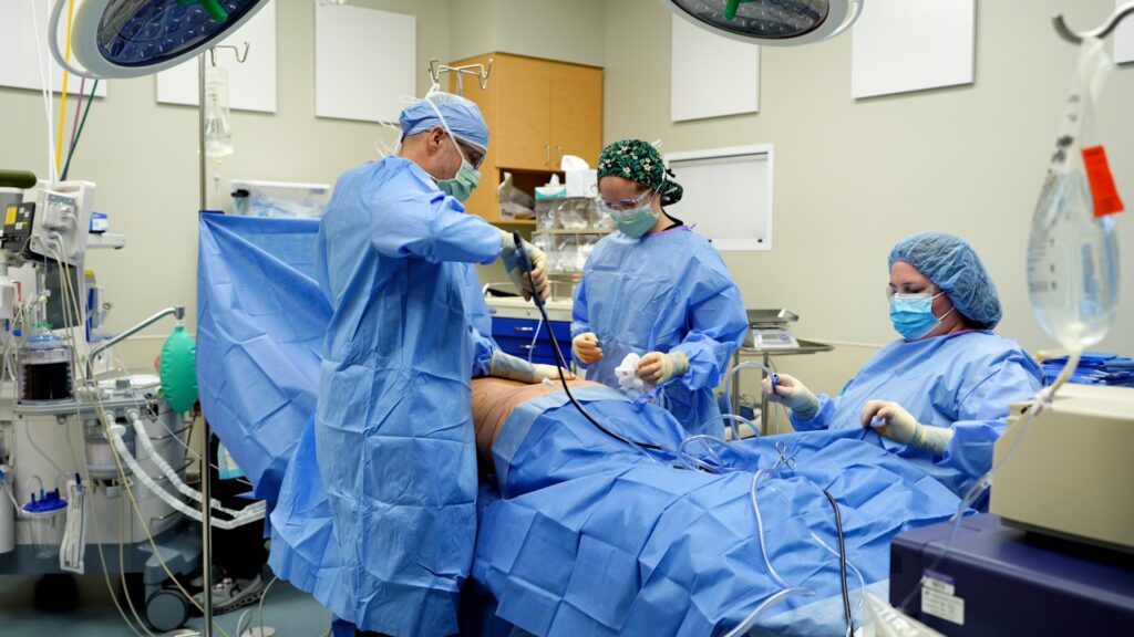 Doctor performing traditional, power assisted liposuction on a patient in the operating room