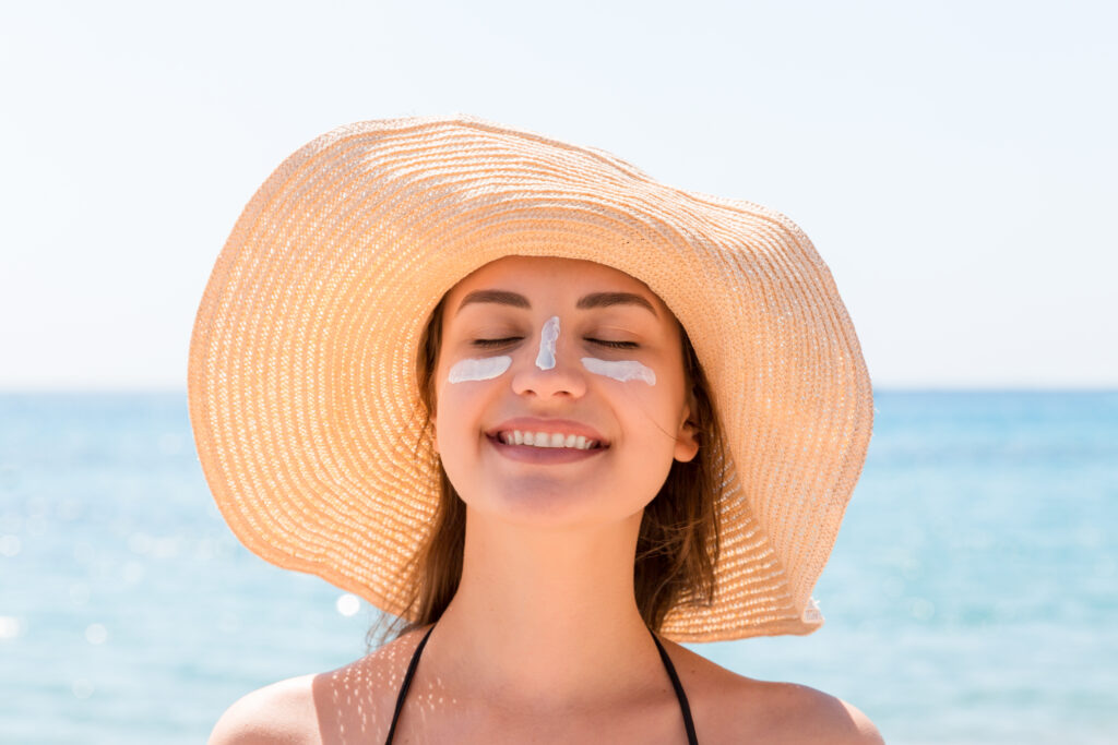 woman in sunhat with sunscreen on face